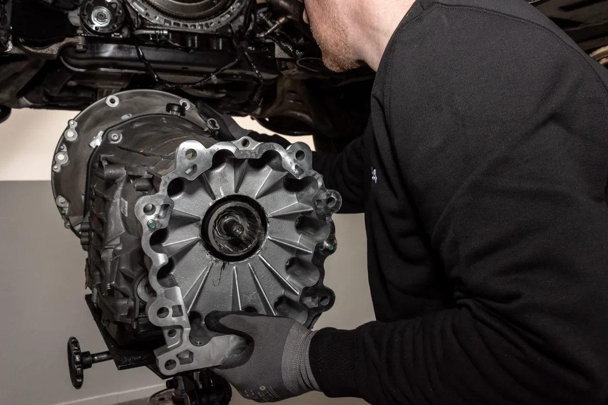 Mechaniker nimmt ein Mercedes-Automatikgetriebe unter dem angehobenen Fahrzeug ab